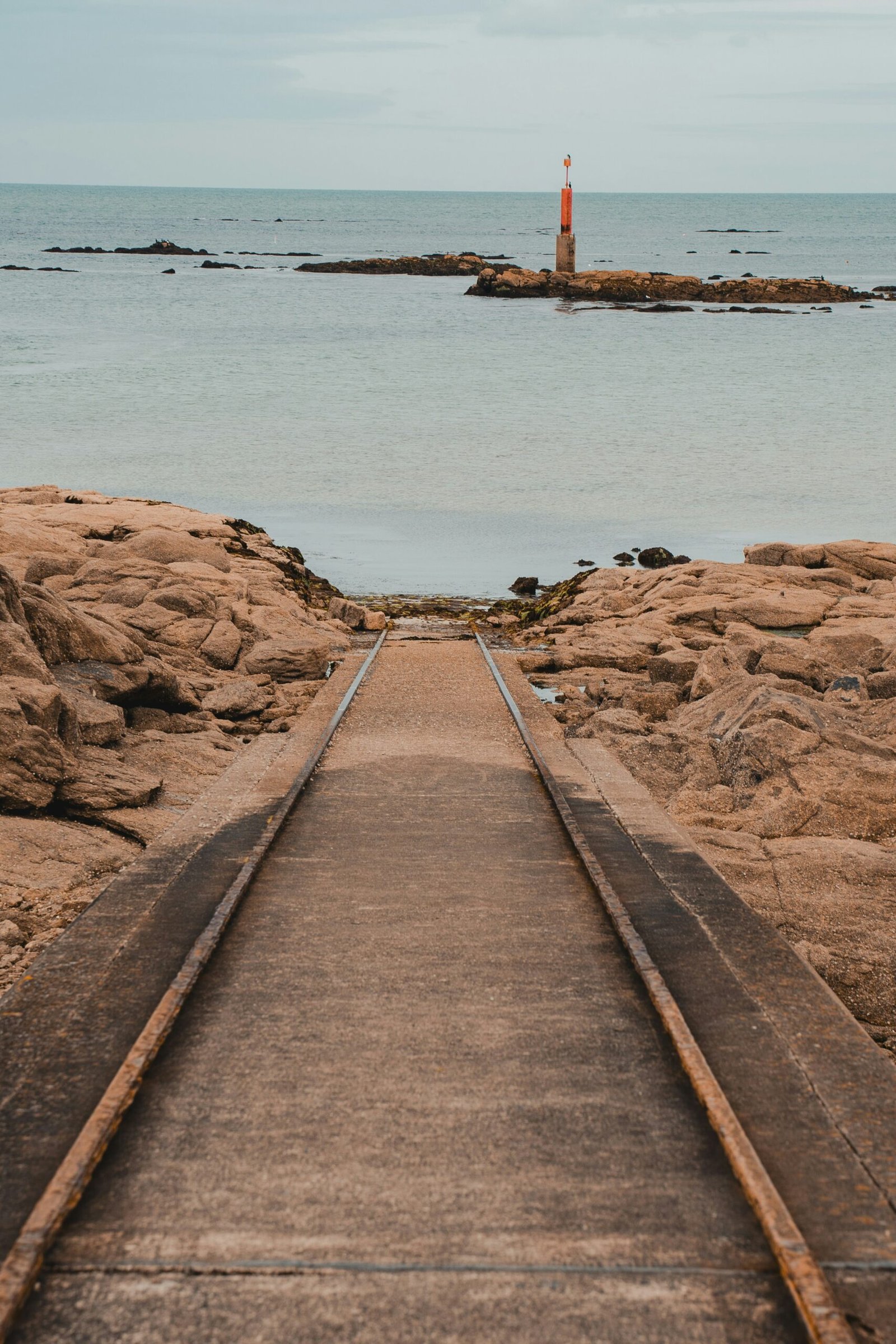 a train track leading to a lighthouse in the ocean