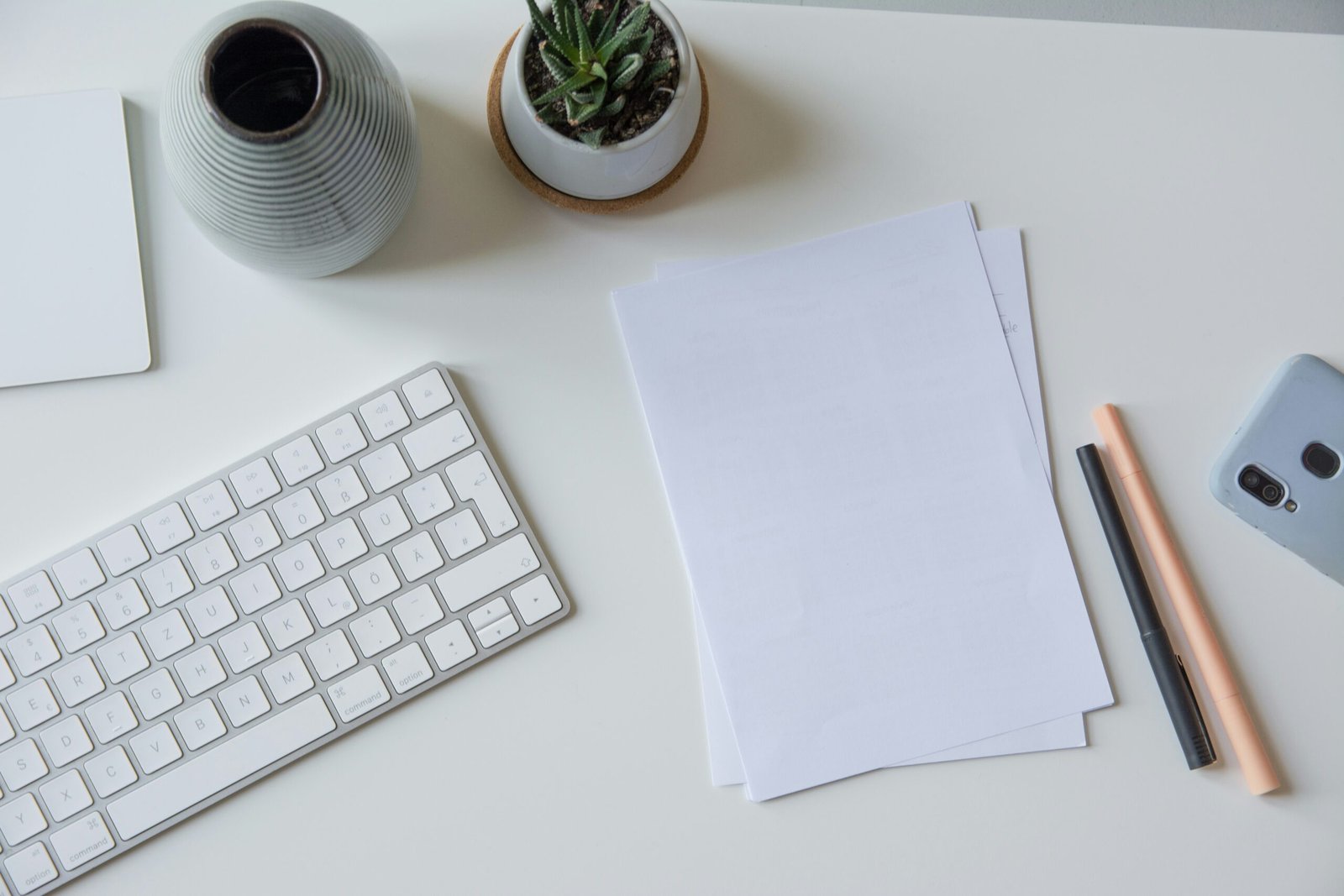 white printer paper beside white apple keyboard